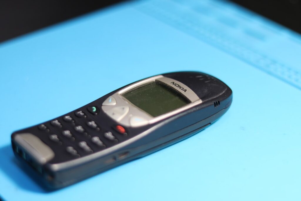 An old nokia phone is on a blue surface.