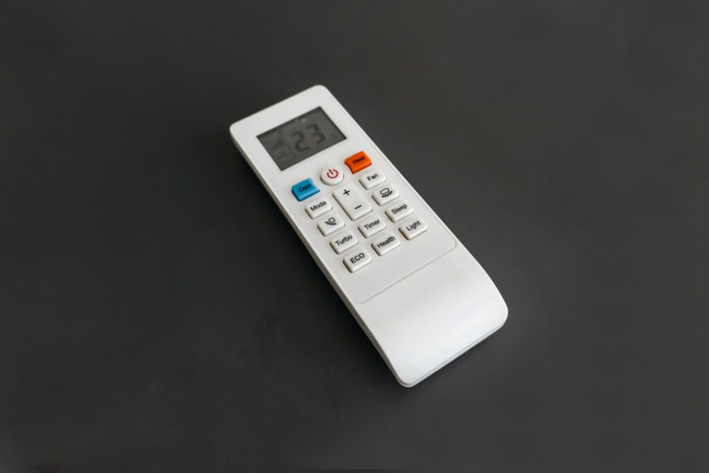 Here's a caption for the image: a white remote control lies on a dark surface.