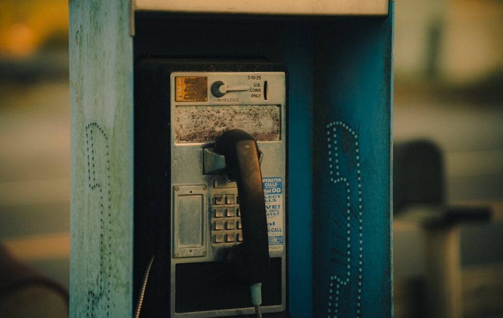 An old fashioned pay phone sitting on the side of a street