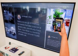 a person holding a cell phone in front of a large screen