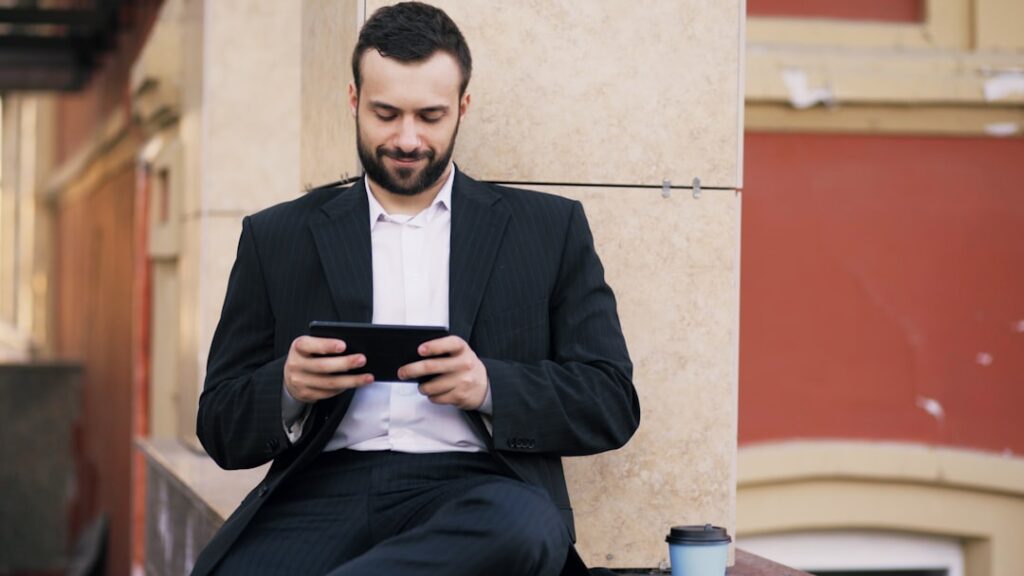 Man in suit looking at phone outdoors smartphone.
