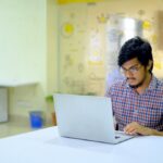 woman in blue and white checkered shirt using macbook